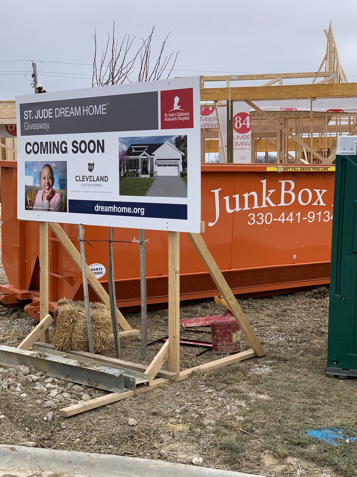 Orange JunkBox Inc. dumpster behind the St. Jude Dream Home Giveaway sign as the house is framed
