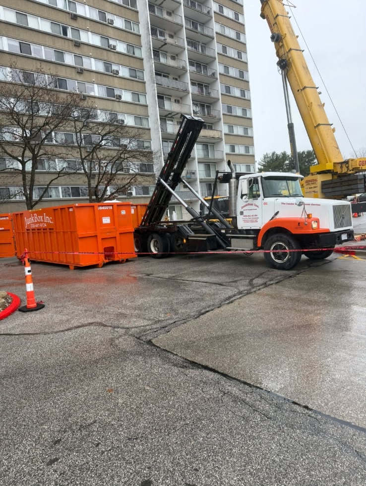 JunkBox roll-off truck setting an empty orange 30-yard dumpster at an apartment property